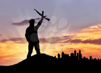 Concept of terrorism. Silhouette of a terrorist with a gun against the evening city