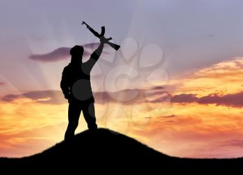 Concept of a terrorist. Silhouette terrorist with rifle at sunset