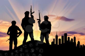 Concept of terrorism. Silhouette of terrorists with a rifle standing on a pile of skulls on the background of evening city
