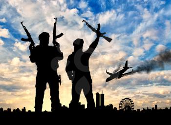 Concept of terrorism. Silhouette of the terrorists and the plane crash on the evening city