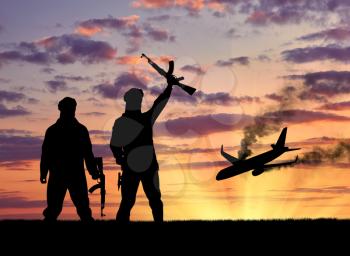 Concept of terrorism and acts of terrorism. Silhouette of terrorists and blow up the plane wreck at sunset