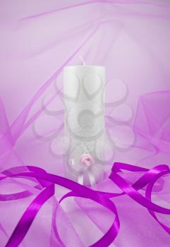  Concept of wedding accessories. Wedding candle on a background of pink fabric