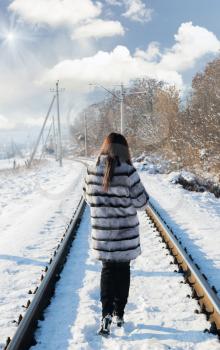 Concept of depression and loneliness. Photo lonely girl in a fur coat walking on railroad