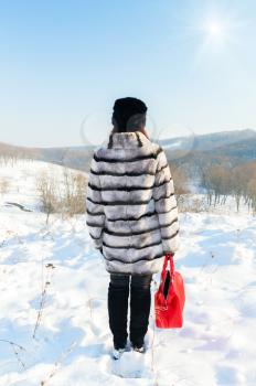 Concept of depression and loneliness. Photo lonely girl in a fur coat standing on a mountain top