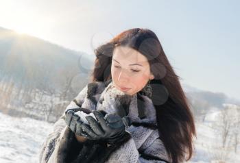 Happiness emotions concept. Young woman blowing in the snow in her hands