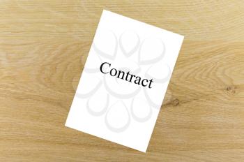 Business concept. A sheet of paper with the word contract on a wooden table