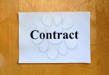 Business concept. A sheet of paper with the word contract on a wooden table