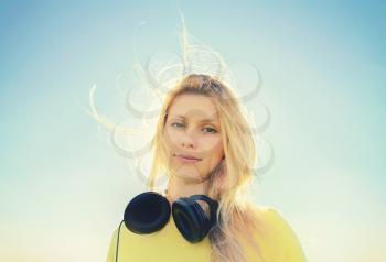 Concept of music. Young woman with headphones on the sky background