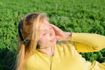Concept of music. Young woman with headphones listening to music on meadow