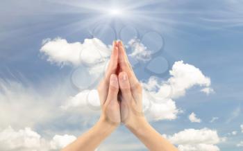 Concept of prayer and religion. Praying hands of man on a background cloudy sky