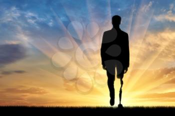 concept of rehabilitation of invalids with prosthetic legs. Walking disabled man at sunset