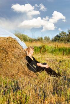 Concept of travel and leisure. Young woman tourist resting near haystack