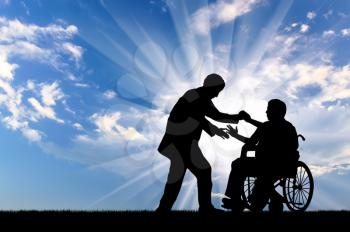 Man helps man in wheelchair to stand up on background sky. Concept help disabled persons