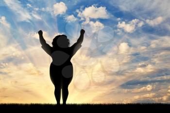 concept of obesity and excess weight. Silhouette of a thick and happy woman on sunset