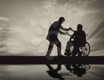 Man helps man in wheelchair to stand up on background black and white. Concept help disabled persons