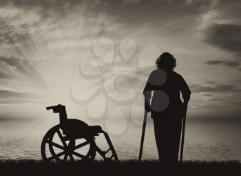 Disabled persons woman on crutches on sea and wheelchair on background of sky. Concept of disability