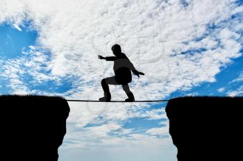 Man walks on a tightrope over a cliff. Concept of business risk