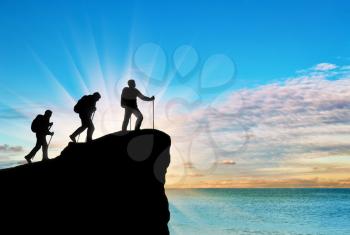 Silhouette climbers ascending to top of mountain on background of the sea. Concept teamwork