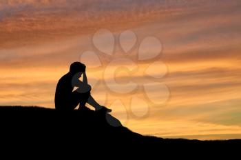 Child abuse and violence. Silhouette of a crying lonely boy on a sunset background