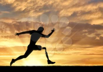 Running a disabled person with a prosthetic leg, confidently running on the ground at sunset