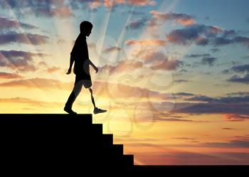 Disabled person with a prosthetic leg descends down the stairs at sunset