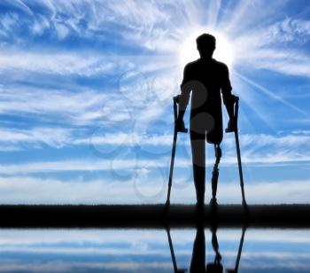 Disabled person with a prosthetic leg and crutches and its reflection in the river
