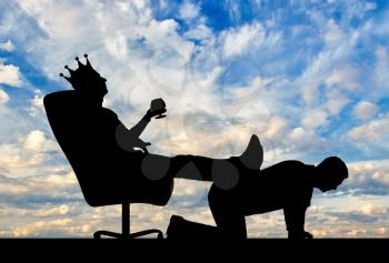 Silhouette of a selfish man with a crown on his head sitting in an armchair, threw back his legs on the man's back. The concept of a businessman is an egoist who does not respect his employees