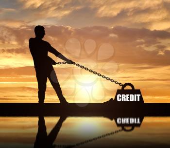 Silhouette of a man chained to a heavy load under the name of the credit. He drags him hard. The concept of credit as a heavy load
