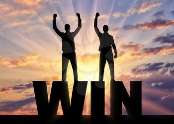 Silhouette of two happy men with raised arms standing on the word win. The concept of winning and mutual benefit of business partners