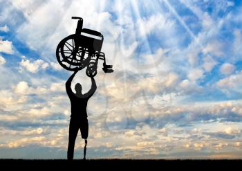 Silhouette of a disabled man standing with a prosthetic leg, raised a wheelchair against the sky. The concept of people with disabilities who can walk again