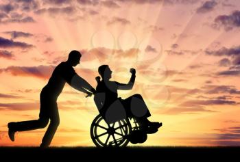 Silhouetted cheerful man having a disabled man in a wheelchair and his friend on a sunset background. Concept of people with disabilities in society
