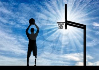 Silhouette of a disabled man with a leg prosthesis intends to throw the ball into the basket. The concept of people with leg prosthesis leading an active lifestyle