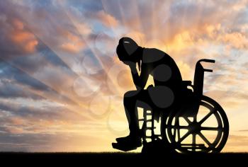 Silhouette of a sad disabled woman in a wheelchair crying. The concept of people with disabilities experiencing grief for the loss of health