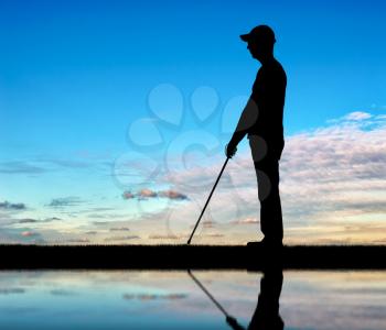 Silhouette of a blind man with a cane in his hand, stands by the river with his reflection. The concept of blind people with disabilities