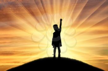 Silhouette of a little happy baby girl standing on top of a hill at sunset. The concept of children's happiness and childhood