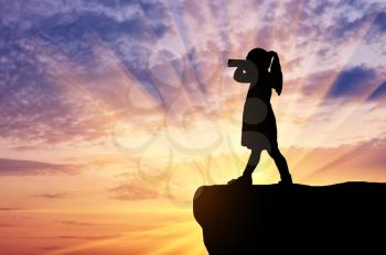 Silhouette of little girl child standing on top looking through binoculars. The concept of children's curiosity and discovery