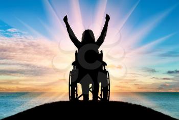 Happy disabled woman in a wheelchair on the background of the sea sunrise on top of a hill. The concept of happy people with disabilities