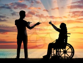Happy disabled woman in a wheelchair on a background of sea sunset, with the man who supports it. The concept of support for people with disabilities