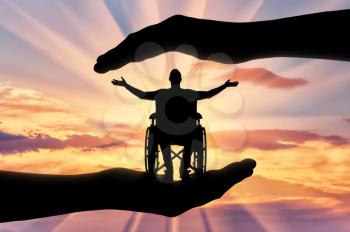 Happy disabled man in wheelchair in hands of help. The concept of caring and helping disabled people