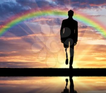 Walking disabled with a prosthetic leg at sunset and rainbow