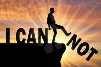 A man standing on a cliff pushes the word - I can not, he achieves the word - I can. The concept of motivation and positive thinking