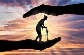 Silhouette of a disabled woman with a walker for the disabled in the hands of help. The concept of protection and assistance to the disabled and the elderly