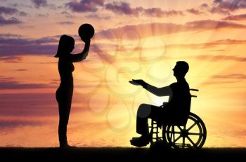 Silhouette of a disabled man in a wheelchair and his wife playing together by the sea. The concept of caring and supporting disabled people in the family