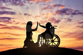 Silhouette of a happy disabled child girl sitting in a wheelchair and her mom beside. Concept of a happy family with a disabled child
