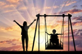 Lifestyle and support for disabled children. Happy child is disabled in a wheelchair on an adaptive swing for disabled children with mom.