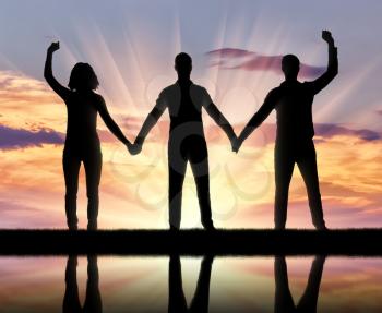 Silhouette of a group of happy people of three people holding hands. The concept of mutual assistance