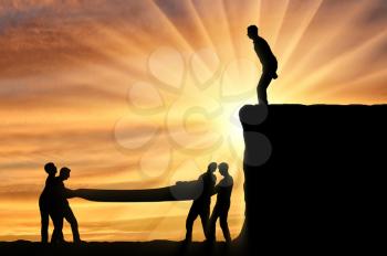 Silhouette of the man intends to make a leap down, people vnitsu help him safely land. The concept of mutual assistance of people