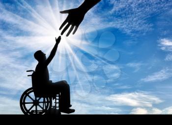 Hand helping an invalid in a wheelchair. The concept of social protection and assistance to people with disabilities