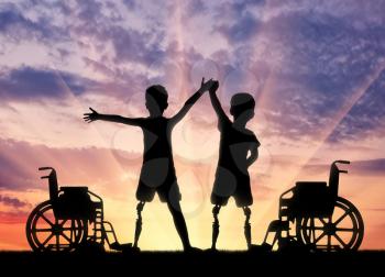 Children's disability concept. Two happy boy with a disability with a prosthetic leg standing near a wheelchair on sunset background