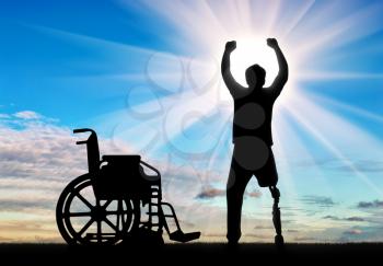 People with disabilities the concept. Happy disabled man with a prosthetic leg standing near a wheelchair at dawn